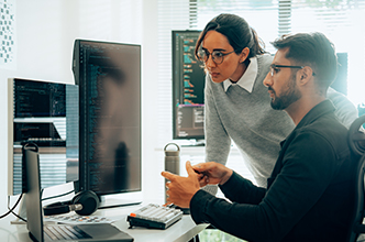 2 collogues looking at a computer monitor